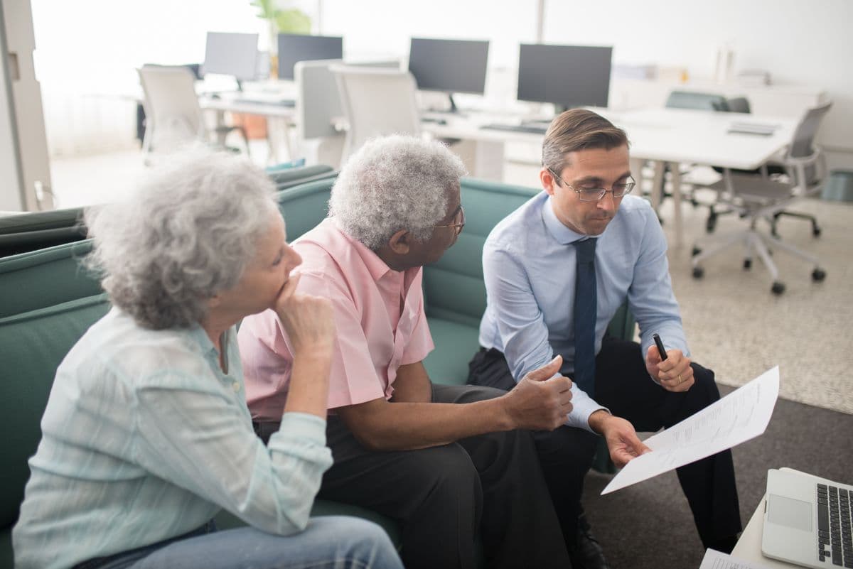 Consultor explicando um relatório de forma transparente a um casal de clientes